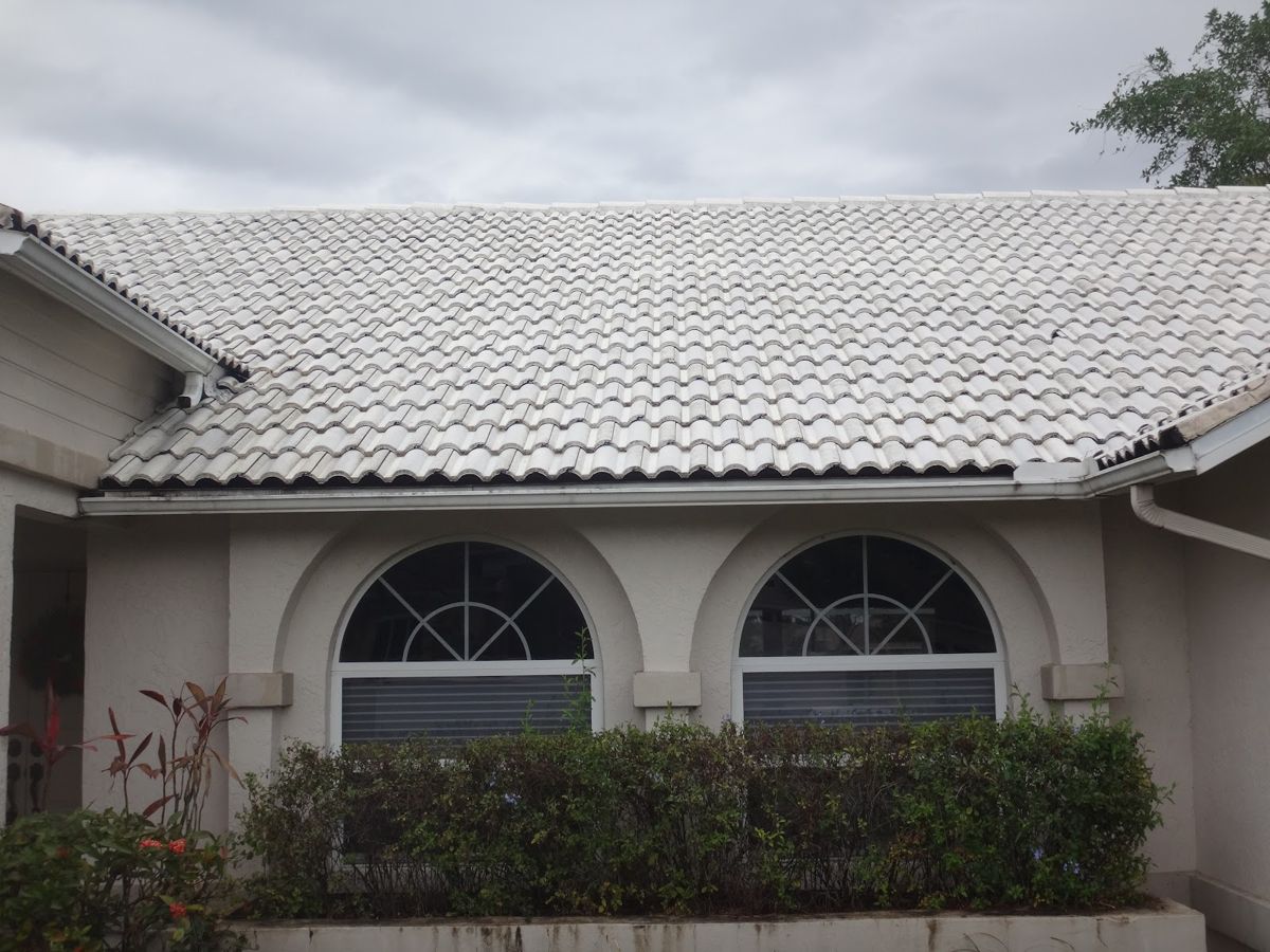 Light grey tile roof and the front of a stucco house with arched windows